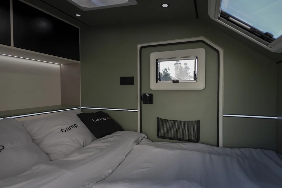 Innenraum des Campella mit Bett und Fenster